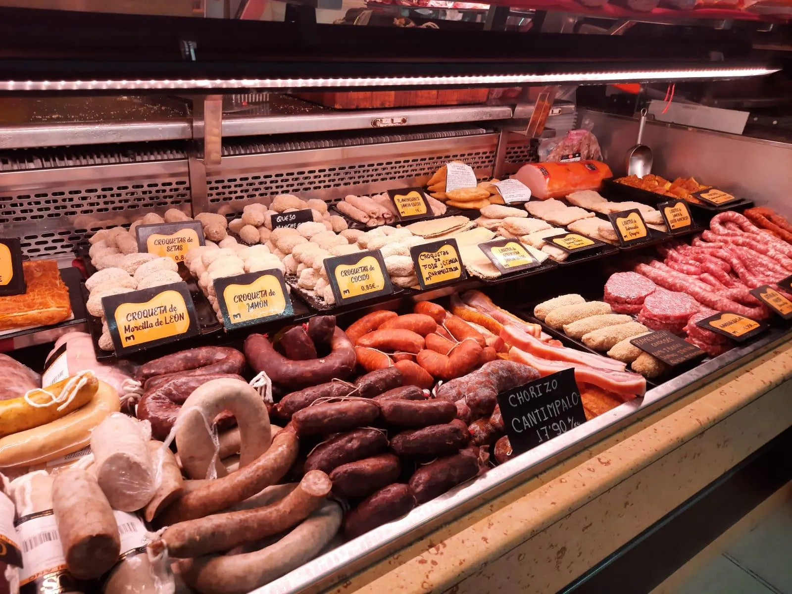 Vitrina con elaboración propia: croquetas, butifarras, chorizos y salchichas, con sus precios