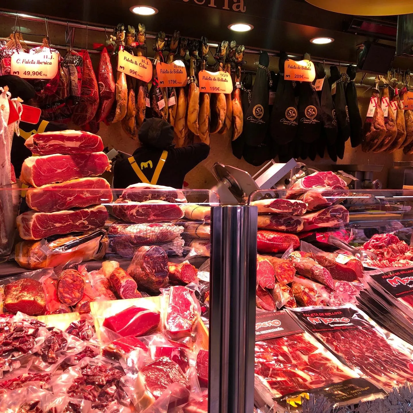 Paletas de jamón de bellota colgando con sus etiquetas sobre la vitrina